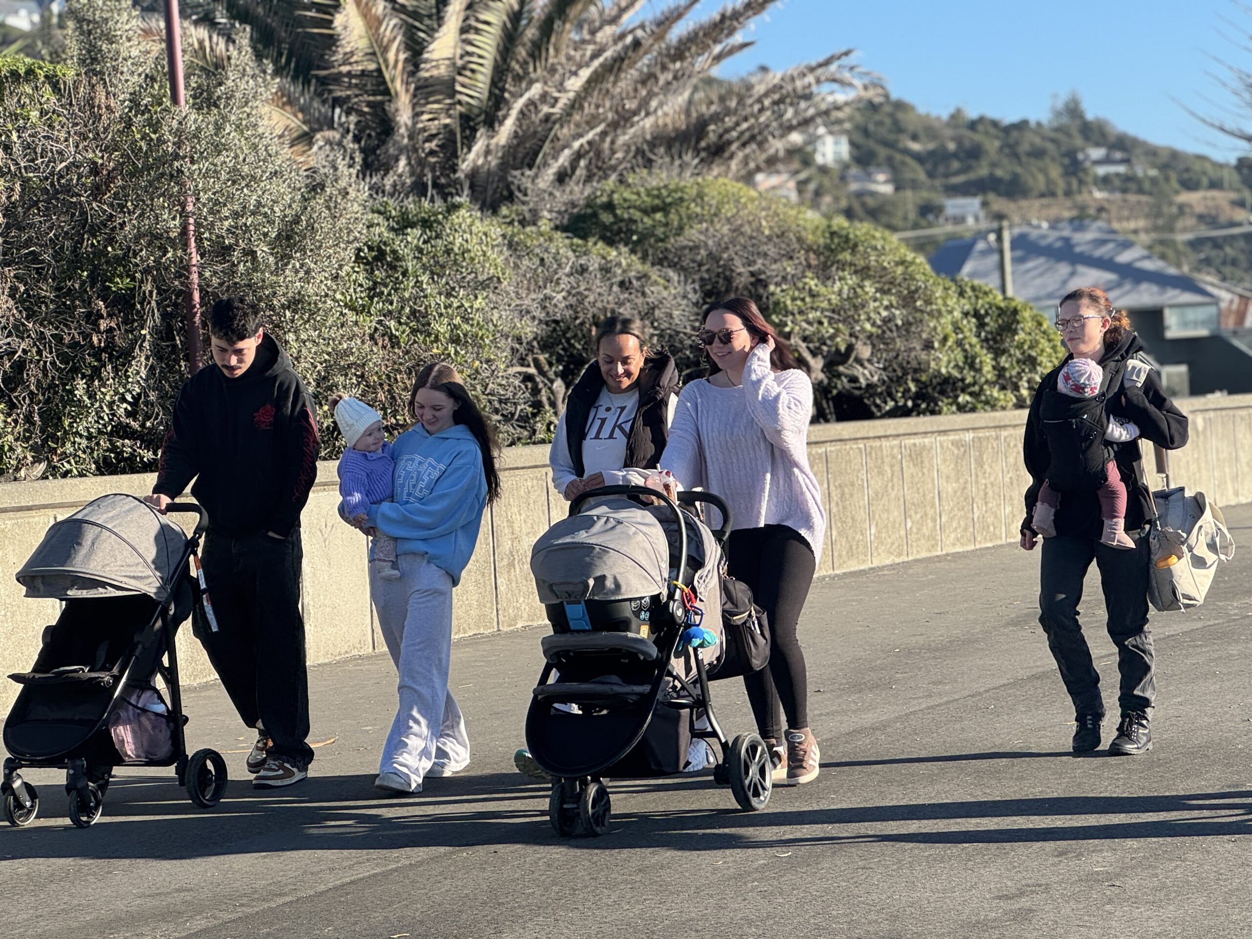 Young parents walking with prams along the promenade